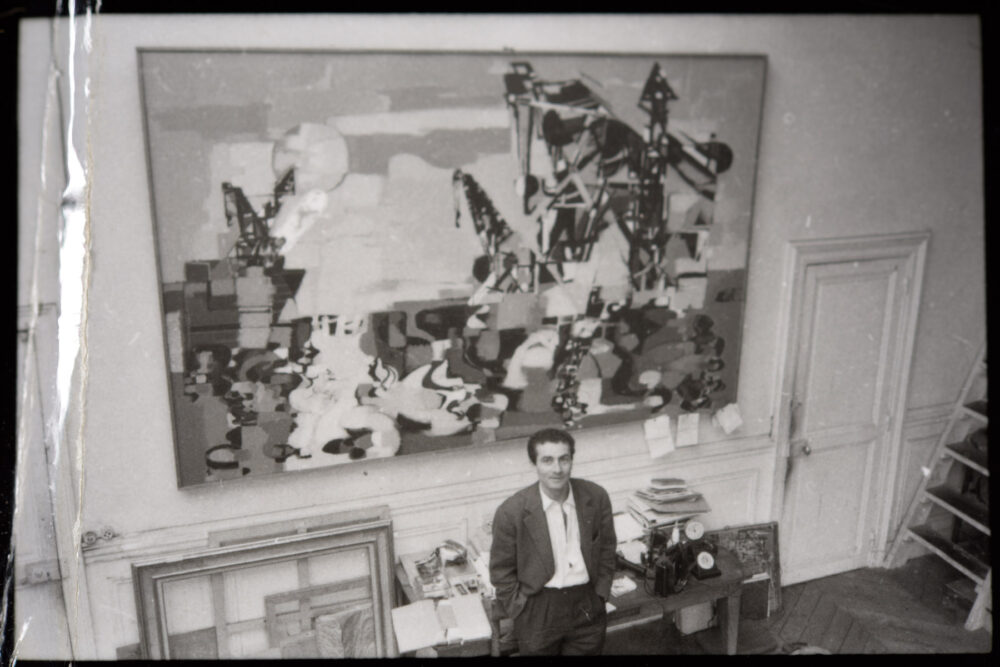 Photo de Georges Arditi dans son atelier de la rue des Martyrs devant son tableau Les Grues vers 1958